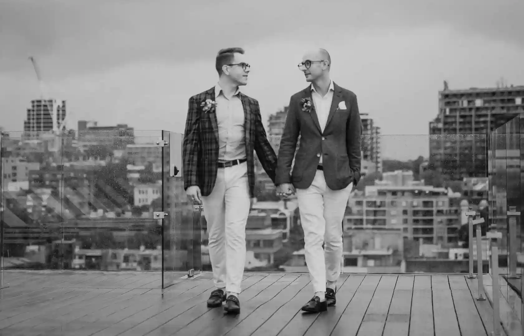 Two grooms walking holding hands at their Sydney apartment rooftop captured by a gay wedding photographer